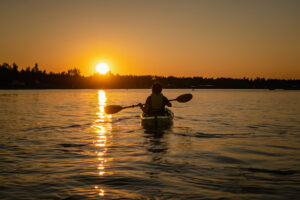 Girl kayaking and taking pause calm sea at midnight in Northern