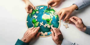 Multiple hands working together to assemble a round world map ji